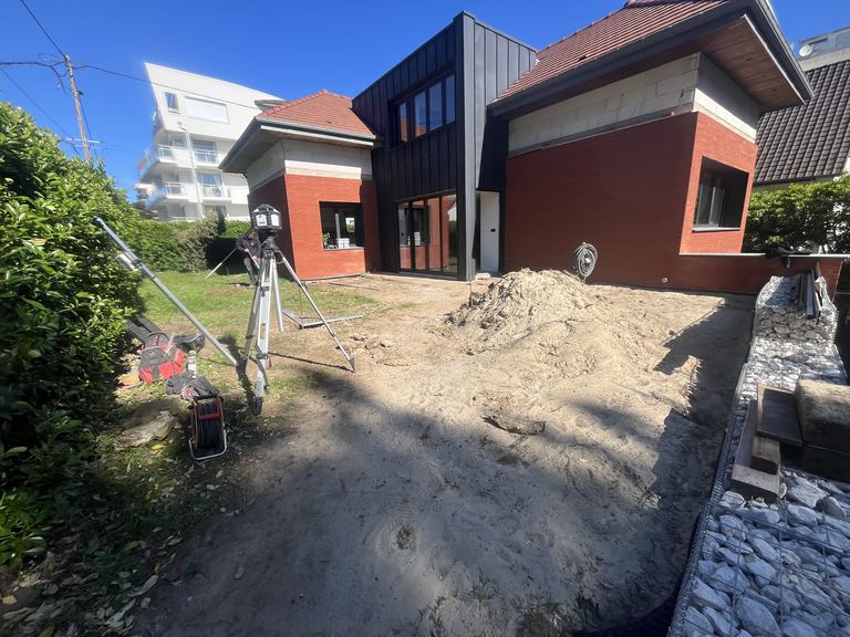Le terrain avant travaux : sable, tas de terre et niveau laser