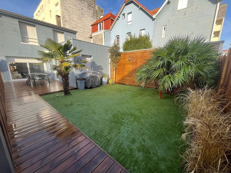 Terrasse bois dans un petit jardin de ville, palmiers conservés