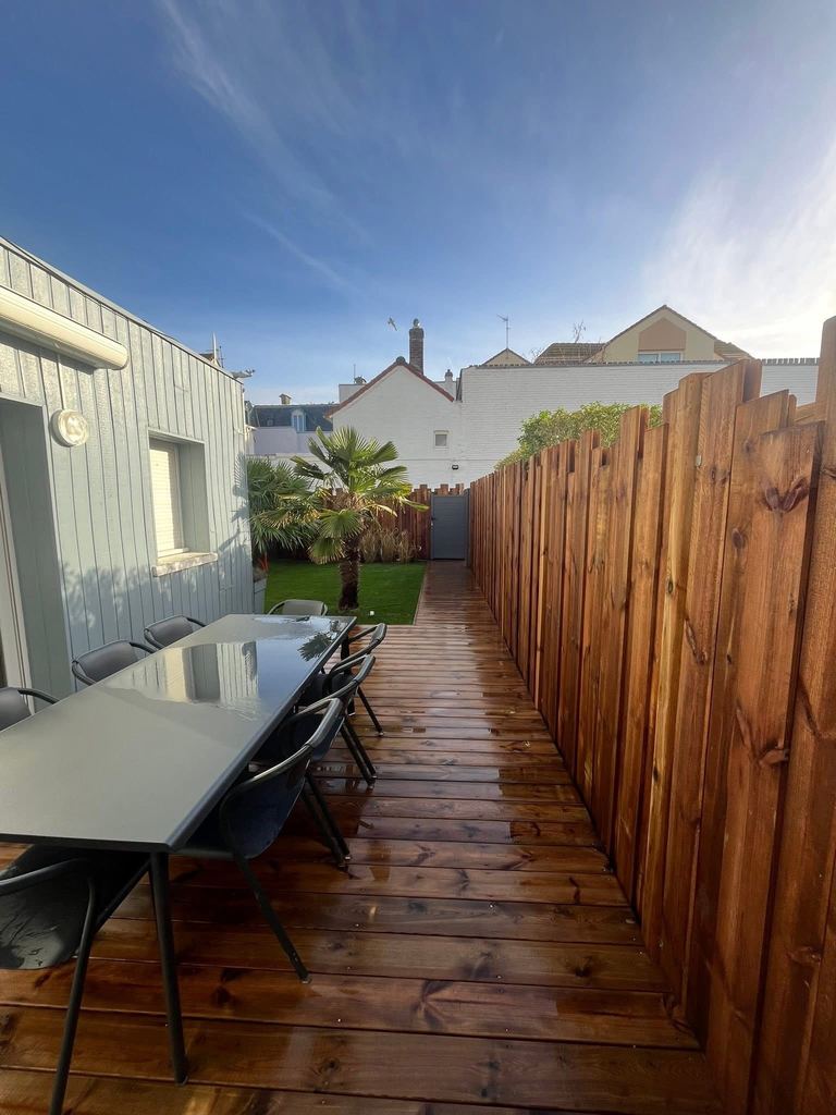 Passage latéral en lames de bois entre une maison et sa palissade