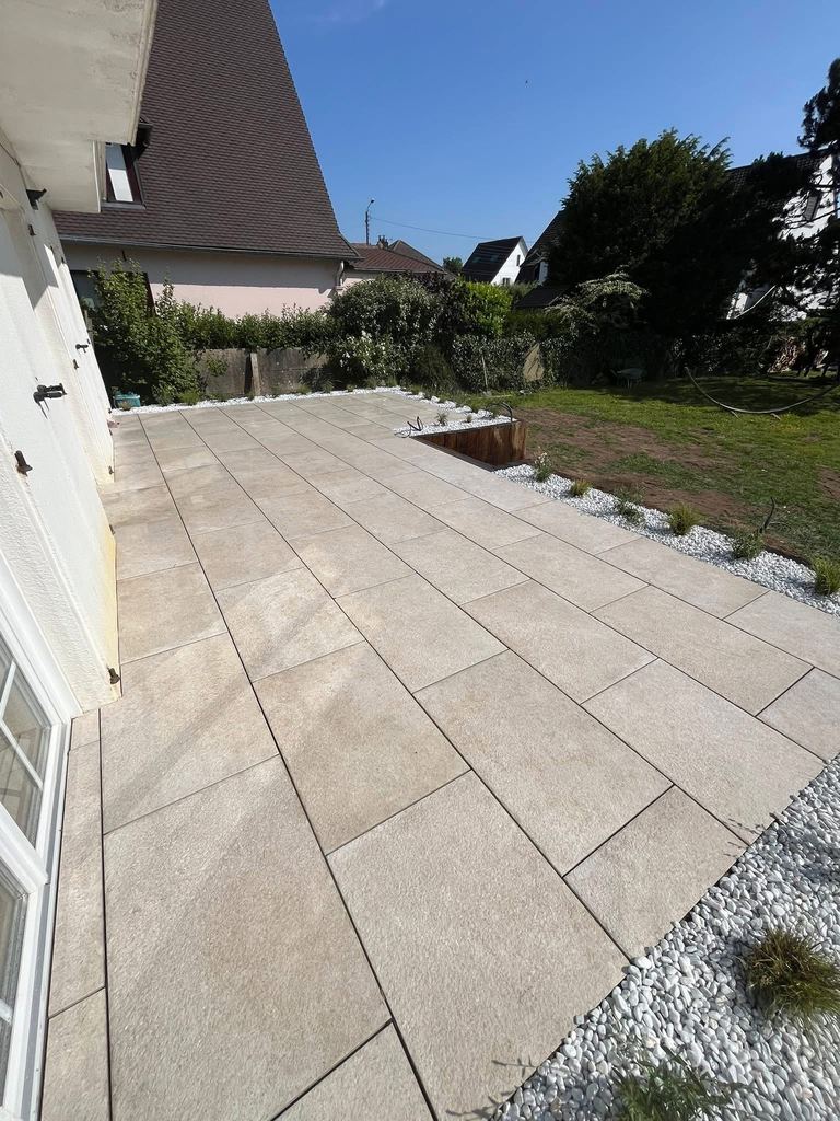 Terrasse en dalles depuis la porte-fenêtre, bordure de galets blancs