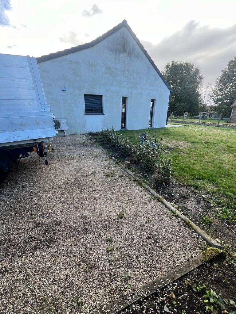 Allée en gravillons le long de la maison, bordée d’une lisse bois
