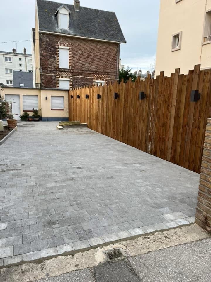 Terrasse pavée d’un hôtel avec clôture bois