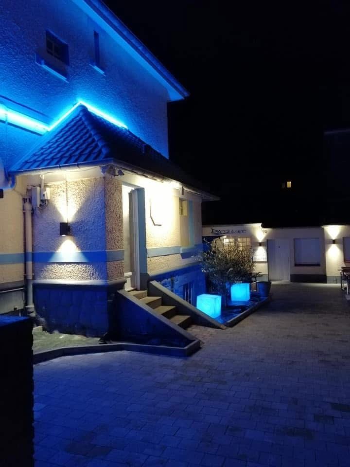 La façade de l’hôtel et la terrasse pavée, éclairées pour le service du soir