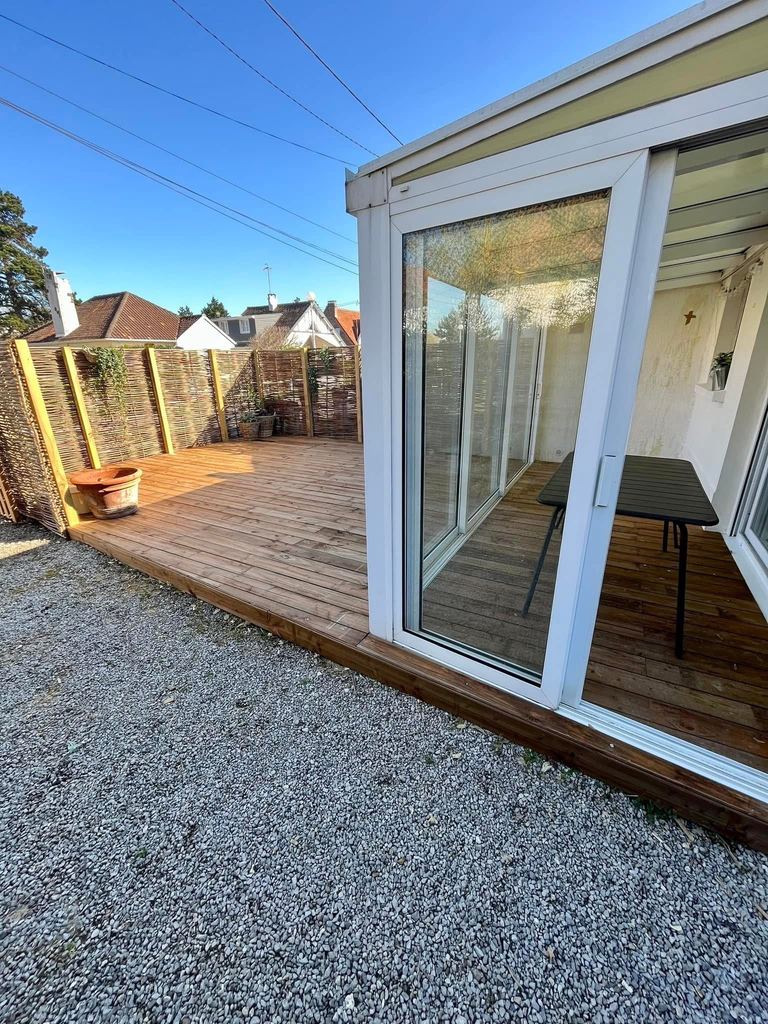 Terrasse bois sortant d’une véranda, entourée de gravier