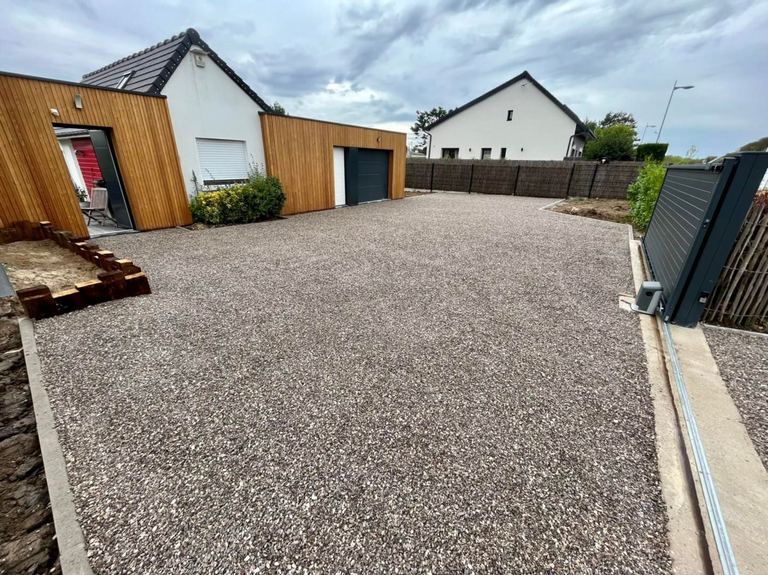 Allée en gravier devant une maison à bardage bois