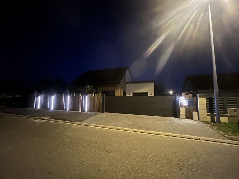Clôture bois éclairée de nuit, vue depuis la rue