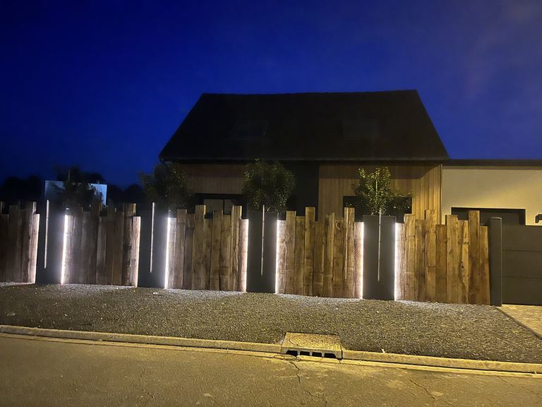 Clôture en lames de bois verticales éclairée de nuit