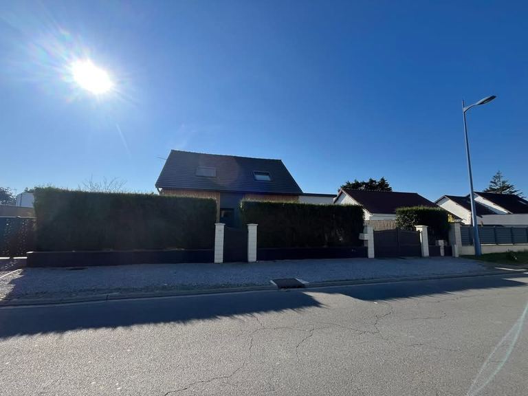 Avant-cour en gravier clair devant une clôture bois et une haie taillée