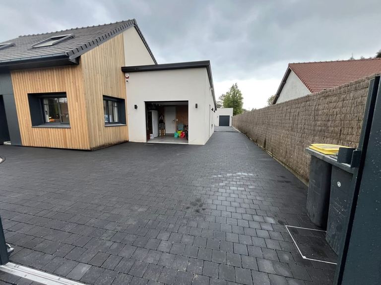 Tour de maison et allée en pavés anthracite devant une maison à bardage bois